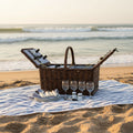 Wicker picnic basket with cutlery, glasses, and a bottle opener on a white background