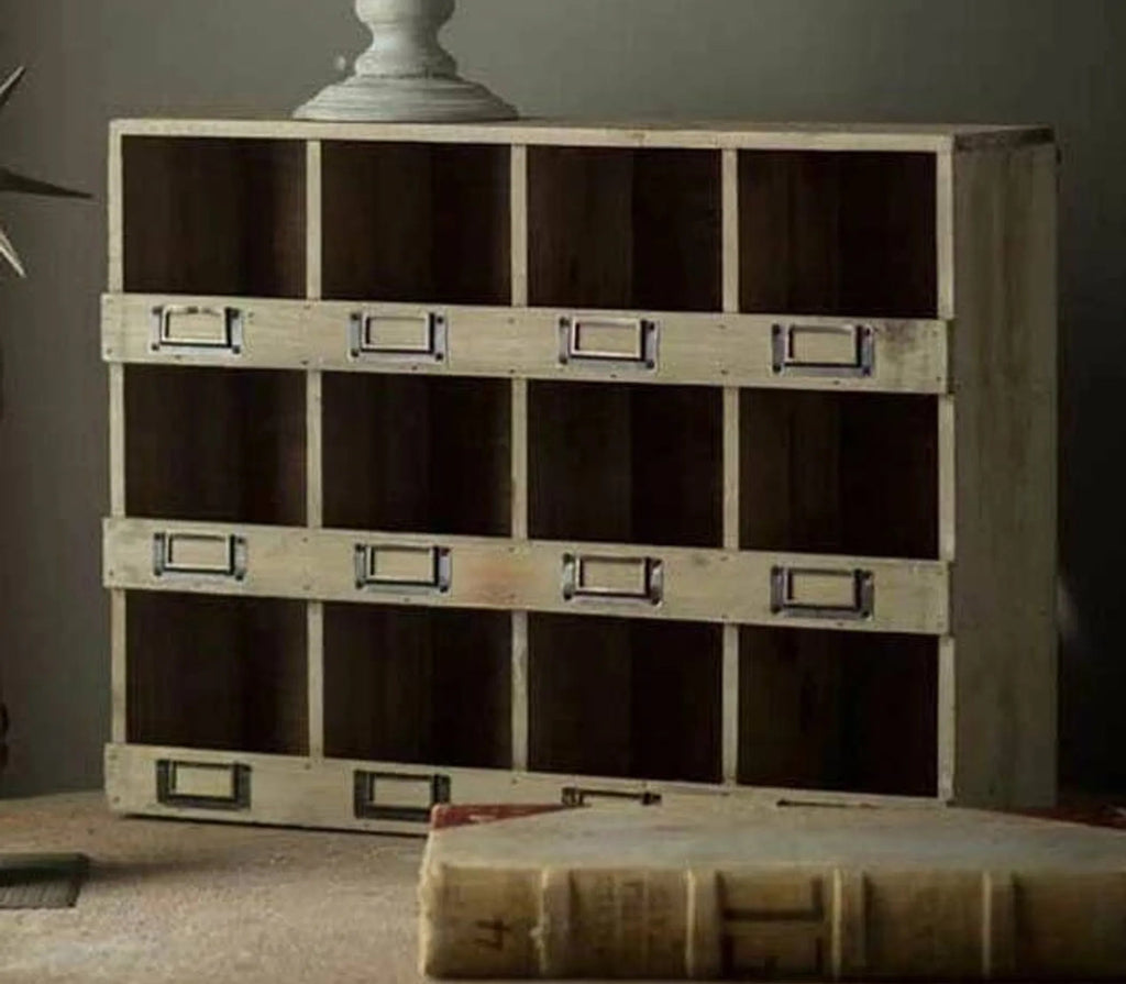 Wooden storage cabinet with metal handles on a table against a gray wall.