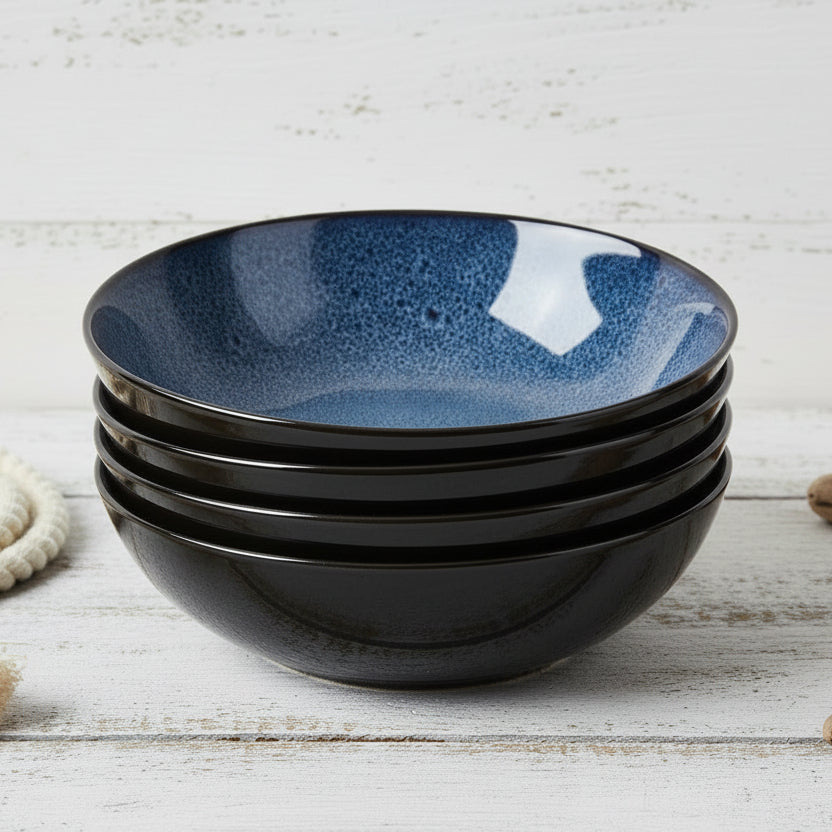 Set of four blue ceramic bowls stacked on a white background
